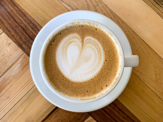 A cup of coffee latte On a wooden table. A mug of flat white coffee on a wooden background. Coffee art. Heart flower shape latte art. Copy space