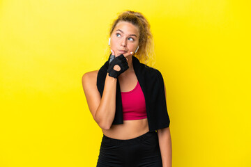 Sport woman with towel isolated on yellow background having doubts and with confuse face expression