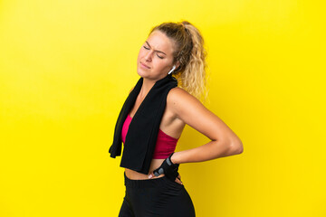 Sport woman with towel isolated on yellow background suffering from backache for having made an effort