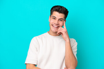 Fototapeta premium Young handsome caucasian man isolated on blue bakcground laughing