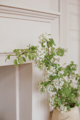 Flowering branches in a vase, fireplace. Minimalistic stylish interior.