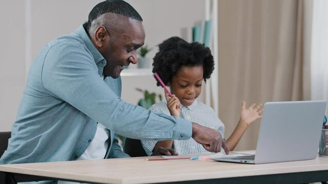 Adult dad explains elementary task to little daughter loving father helps cute funny kid girl to do homework tutor teaches child happy african american family having fun together homeschooling concept