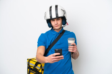 Young caucasian man with thermal backpack isolated on white background holding coffee to take away and a mobile