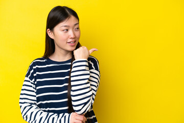 Fototapeta premium Young Chinese woman isolated on yellow background pointing to the side to present a product