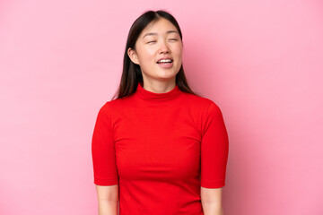 Young Chinese woman isolated on pink background laughing