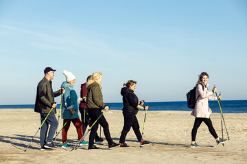 Female leader sportswoman and group joying Scandinavian, Nordic walking with professional sticks...