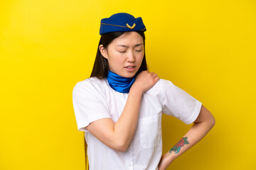 Airplane Chinese woman stewardess isolated on yellow background suffering from pain in shoulder for having made an effort