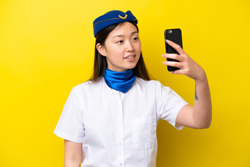 Airplane Chinese woman stewardess isolated on yellow background making a selfie