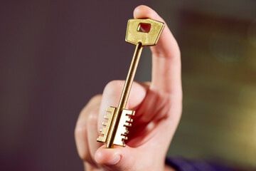  Close up of human hand holding golden key