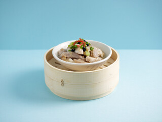 steamed spare ribs with black bean sauce and minced garlic served in a wooden bowl with chopsticks...