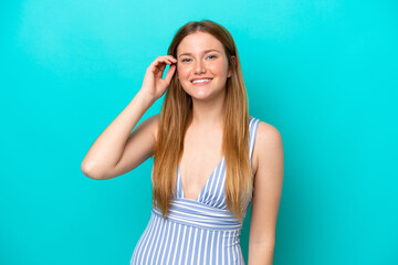 Young woman isolated on blue background in swimsuit in summer holidays