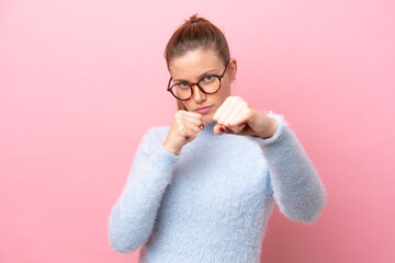Young caucasian woman isolated on pink background with fighting gesture