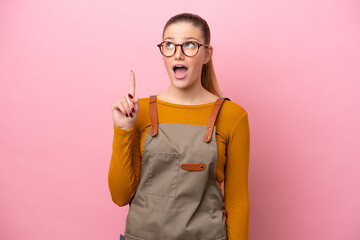 Woman with apron isolated on pink background thinking an idea pointing the finger up