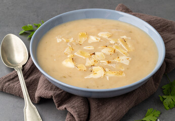 Onion soup with cheese in a bowl and seasonings over stone background