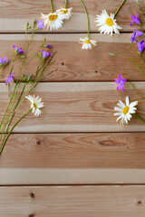 Flowers made of bluebells and daisies on a light wooden background. Layout. Congratulations. Holiday. Birthday. A flat copy space with a top view.