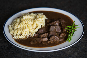 ready to eat - roasted heart, kidneys and liver from a red deer calf with noodles, brown sauce and rosemary at the hunting season