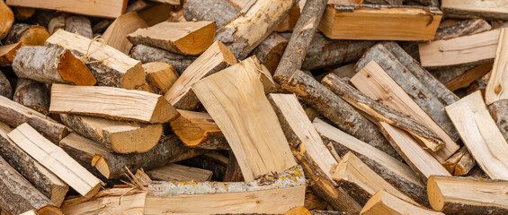 A pile of stacked firewood, prepared for heating the house. Firewood for ready heating in winter.Chopped firewood.environment background.Banner,advertisement.