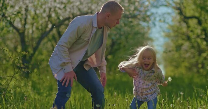 funny game of dad and daughter in garden in summer day, blow away dandelion, 4K, Prores
