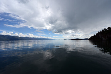 Beautiful dramatic summer cloudscape over Flathead Lake in Montana on calm June day.