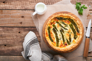 Quiche. Homemade asparagus pie or quiche with cheese and spinach on old wooden table background....