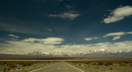Traveling along the asphalt highway across the arid desert and into the Andes cordillera, under a...