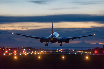 Fototapeta premium Airplane landing on runway with colour sky