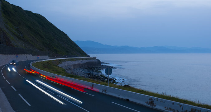 Car lights on the road at dusk by the sea, Euskadi