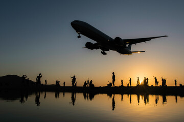 Silhouette airplane and people while landing gear is down during sunset hours 