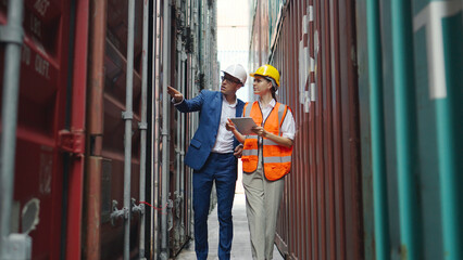 Young engineer and chief inspecting warehouse, containe.