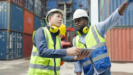 Container terminal employees walking and checking container cargo in warehouse