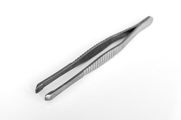 Close-up of metal tweezers on a blurred white background. Anatomical forceps, health and beauty accessories concept