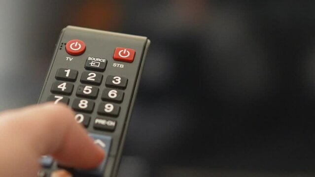Changing channels on television with remote control extreme close-up shot