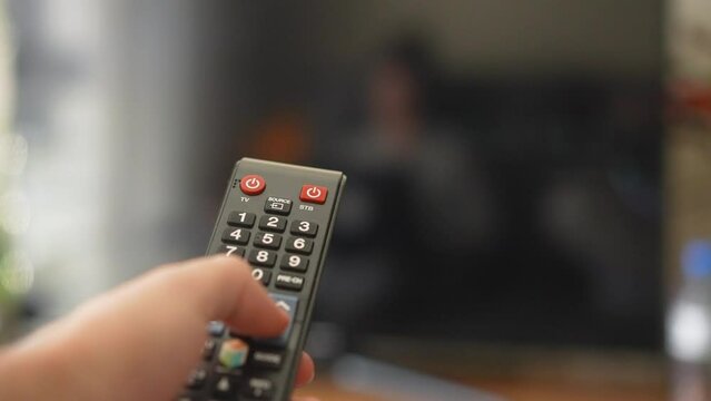 Changing television channels with tv remote controller close-up shot