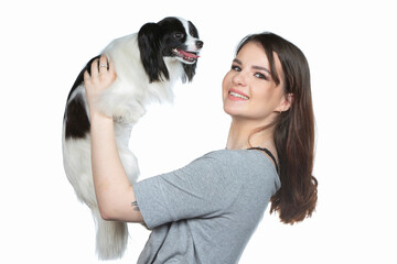 A cute young woman is hugging her papillon puppy. Love between owner and dog. Girl with dog studio portrait.