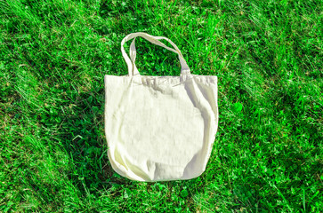 Beige cotton shopping bag on a background of green grass. Zero waste, no plastic, eco-friendly...