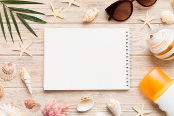 Blank writing book with summer beach accessories on background, copy space. Flat lay with copy space