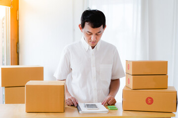 smiling person moving into new home, Portrait of Asian man packing box and check list in the office...