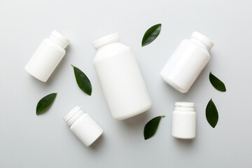 supplement pills with medicine bottle health care and medical top view. Vitamin tablets. Top view mockup bottle for pills and vitamins with green leaves, natural organic bio supplement, copy space