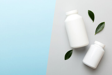 supplement pills with medicine bottle health care and medical top view. Vitamin tablets. Top view mockup bottle for pills and vitamins with green leaves, natural organic bio supplement, copy space