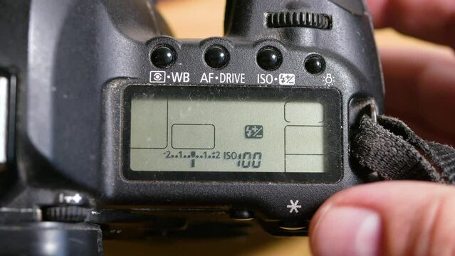 Photographer adjusting exposure modes on a SLR camera