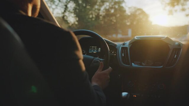 Man drives a car along the road, the setting sun shines in the windshield