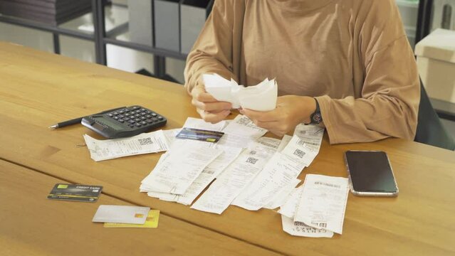 Portrait of stressed Asian woman, audit person and confused by calculate expense from invoice or receipt bills debt. No money to pay, mortgage or loan,bankruptcy at home.People lifestyle