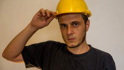 Worker with yellow safety hat for construction site work. Young white caucasian man with short hair and dark eyes.