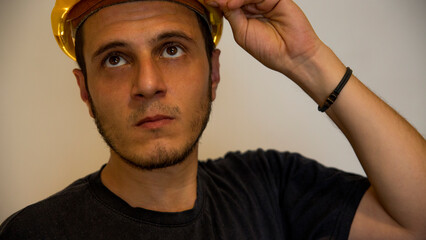 Worker with yellow safety hat for construction site work. Young white caucasian man with short hair and dark eyes.