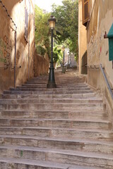 Fototapeta na wymiar stone steps with lampposts in the middle, graffiti on the wall, hand rail on other side, Corsica, France