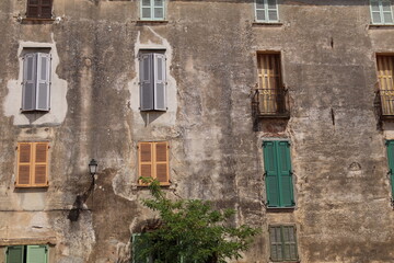 Obraz premium House, windows with shutters, balcony, bright colours against a washed stone wall, Corsica, France