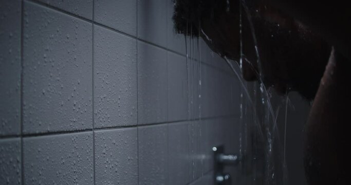 A young black man taking a hot steaming shower.