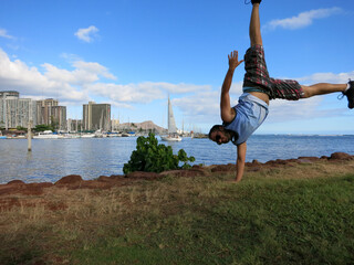 Man does one handed handstand along the shore of Magic Island