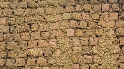 section of a old unbaked brick wall surface, also known as sun dried clay brick wall, earthen buildings used widely in many remote areas, abstract background