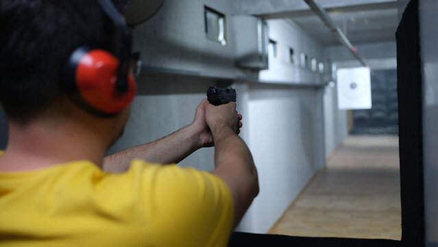 Shooter shoots from pistol in shooting range closeup